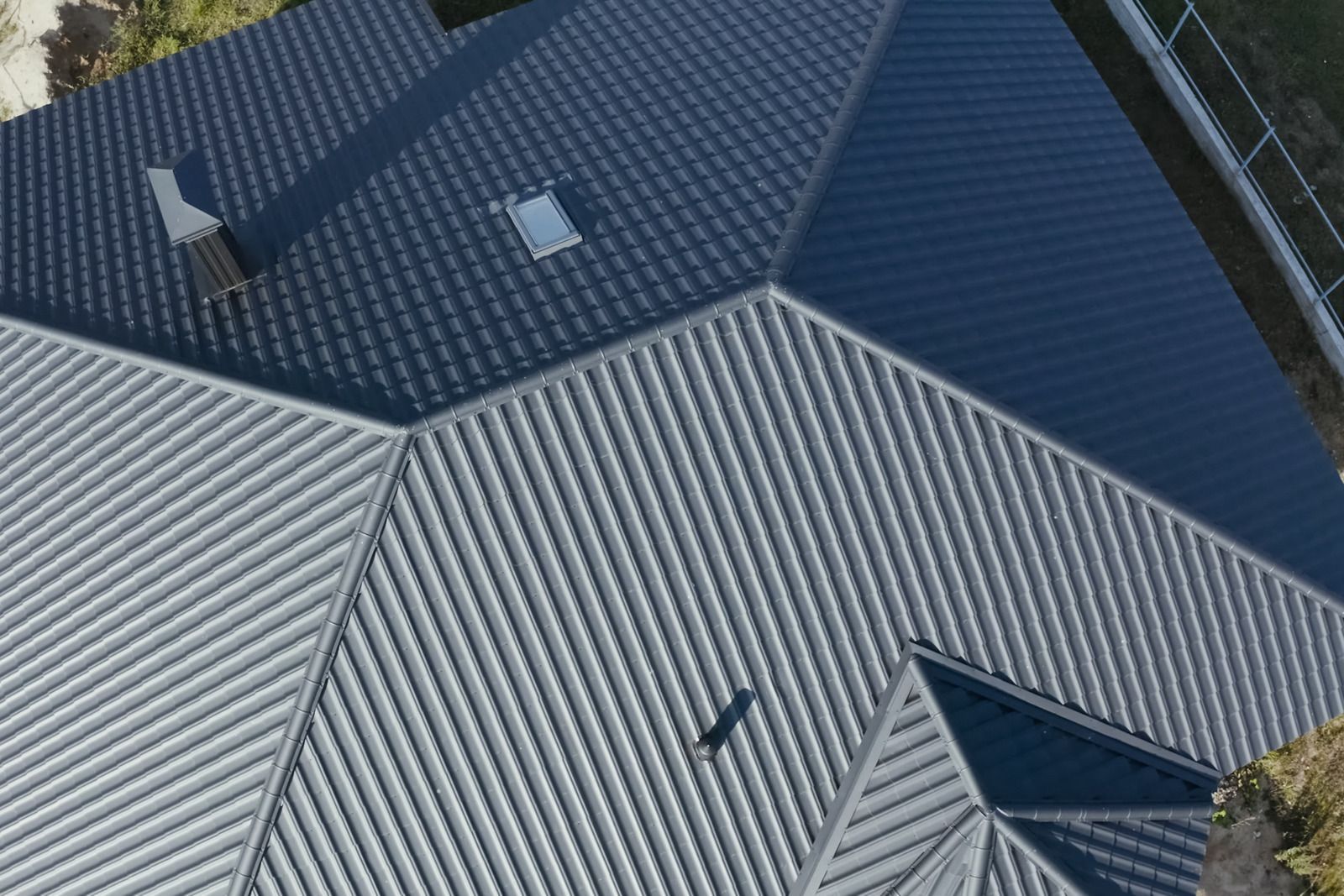 Overhead view of a house roof, various angles and colors, gray and black corrugated metal panels.