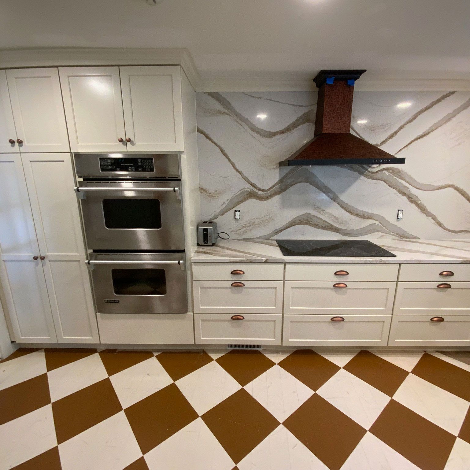 A kitchen with white cabinets stainless steel appliances and a checkered floor