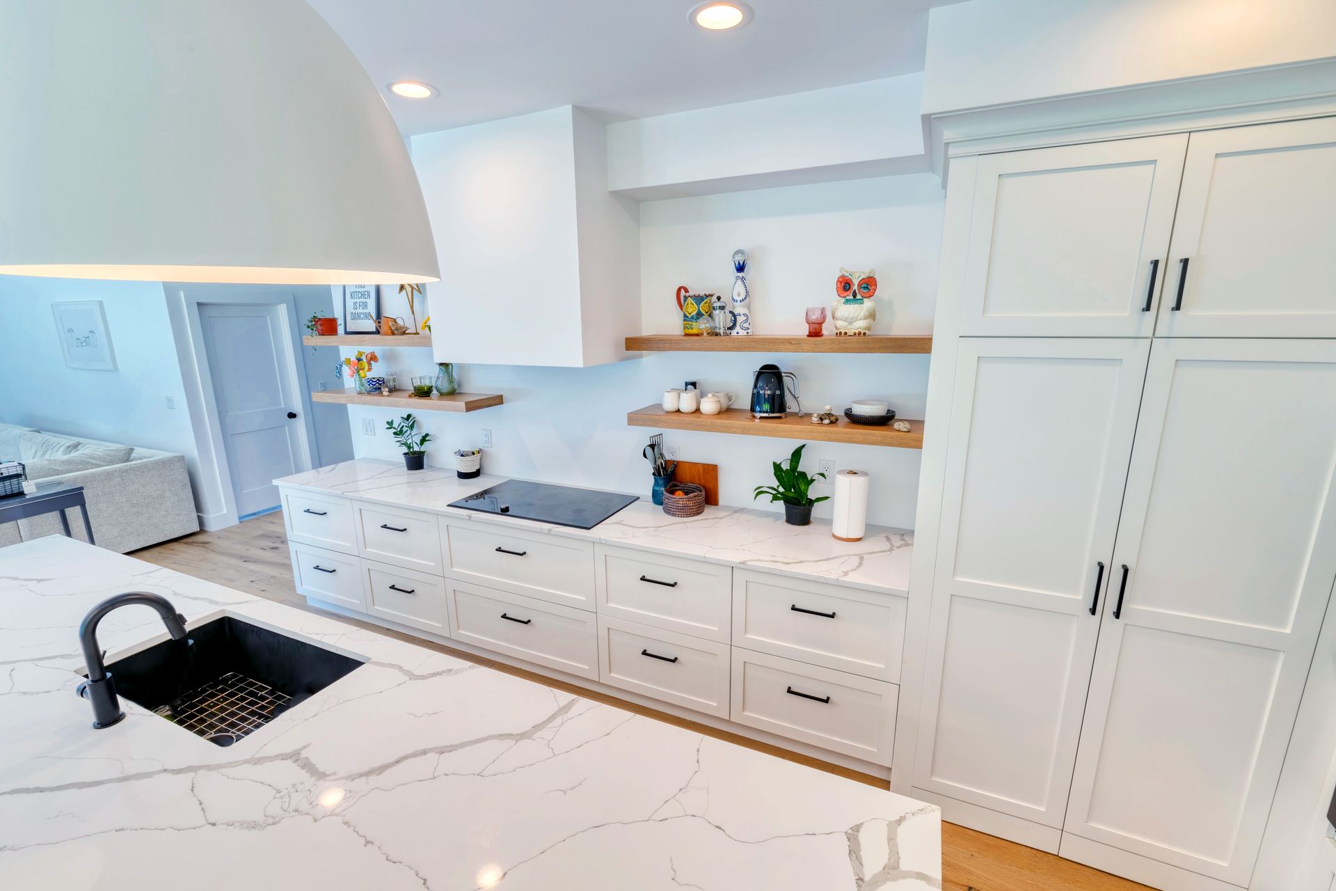 A kitchen with white cabinets , a black sink , and a stove top oven.