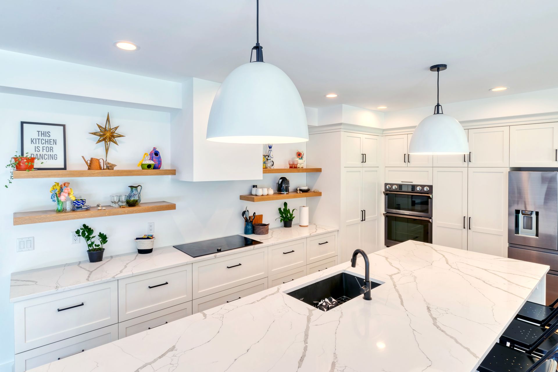 A kitchen with white cabinets , a large island , a sink , and a stove.