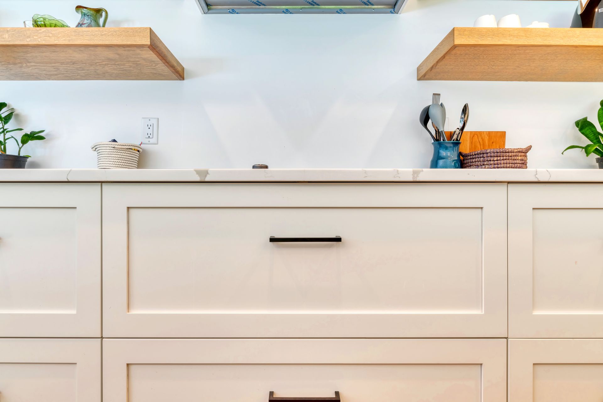 A kitchen with white cabinets and wooden shelves.