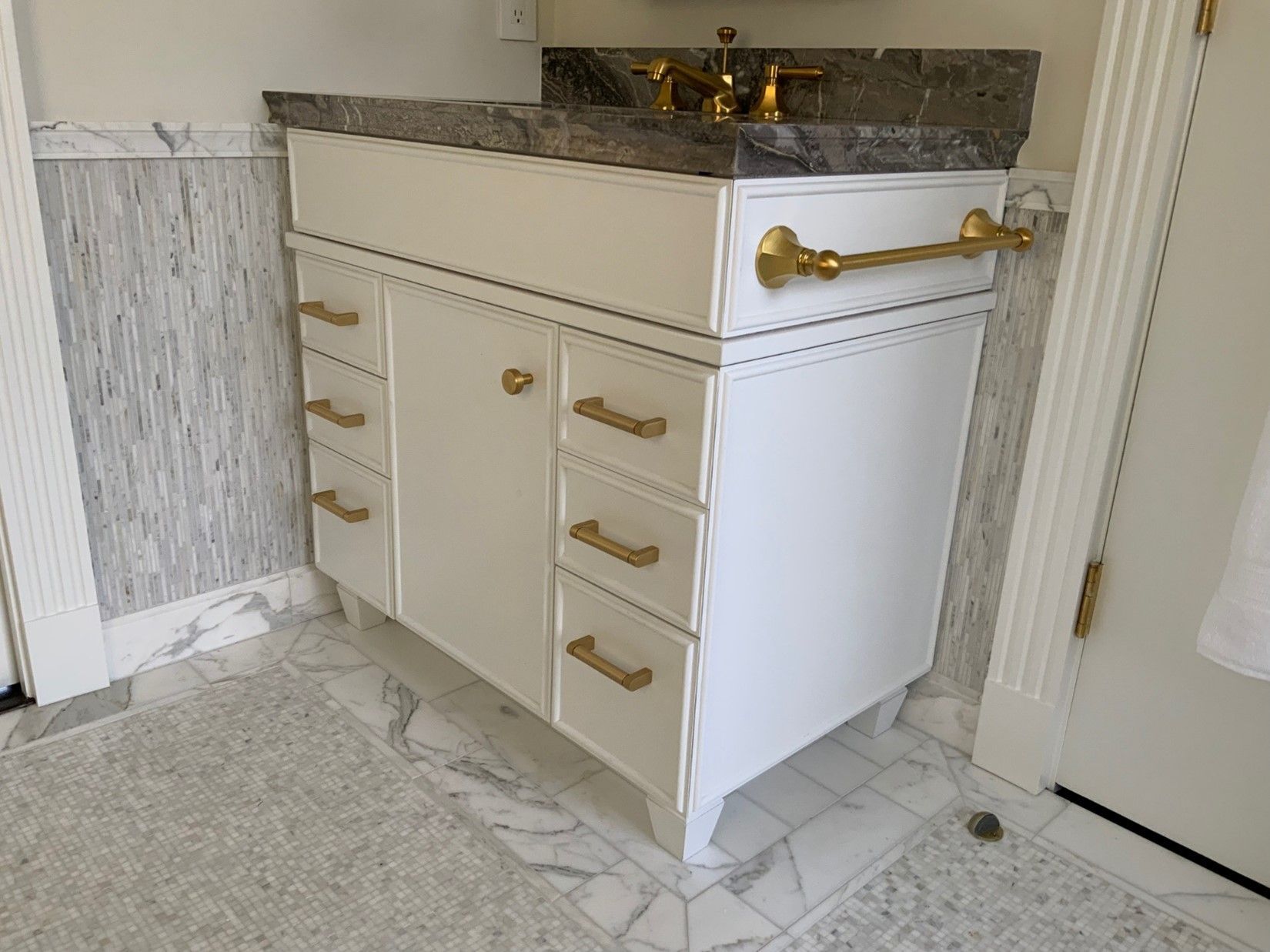 A bathroom vanity with a sink and a marble counter top.