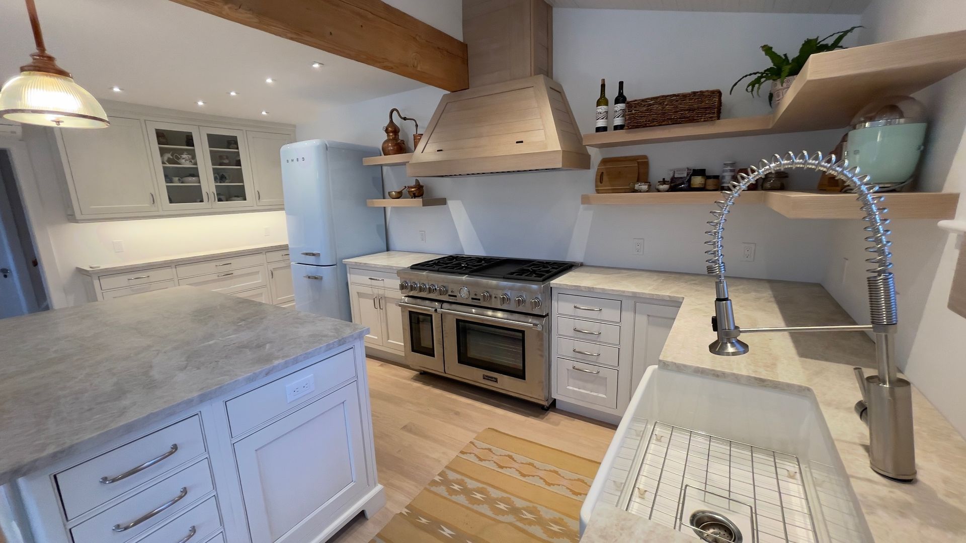A kitchen with white cabinets , a sink , a stove , and a refrigerator.