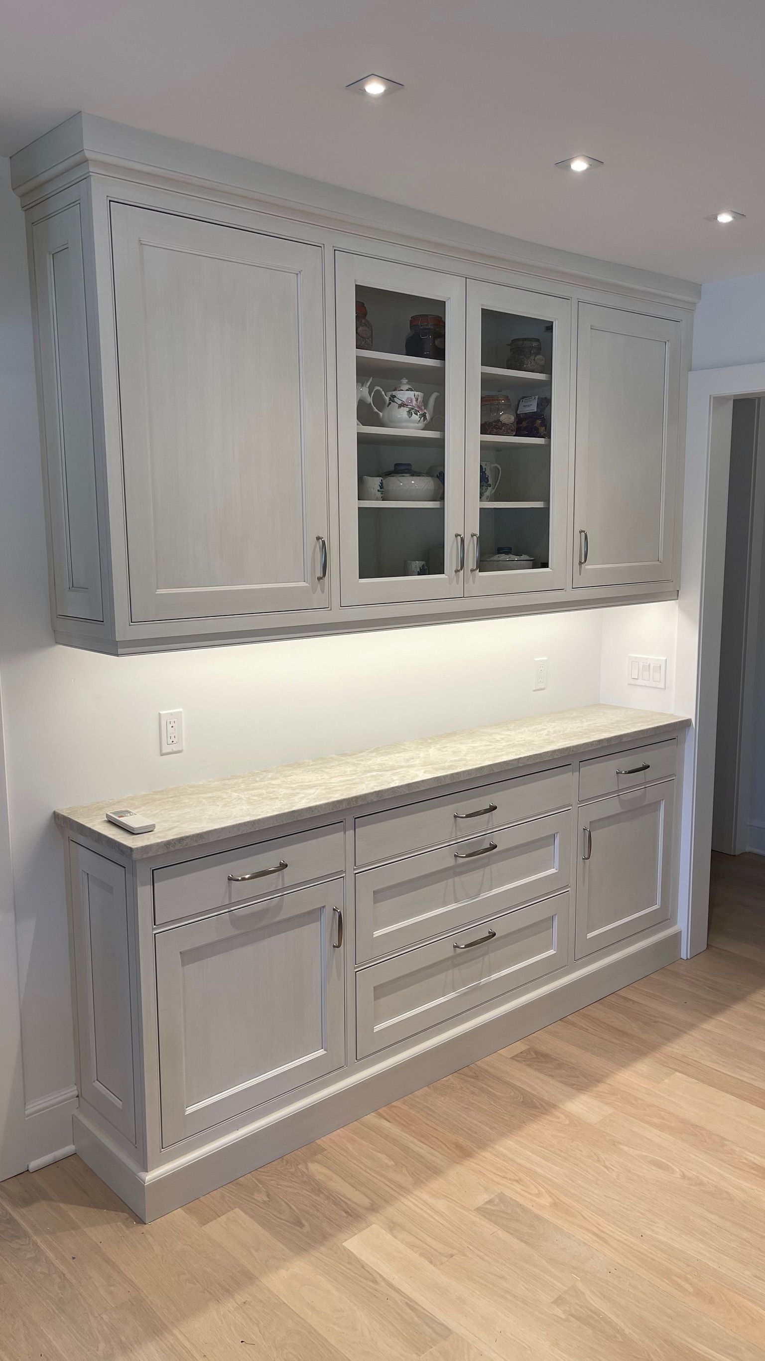 A kitchen with white cabinets and a wooden floor.