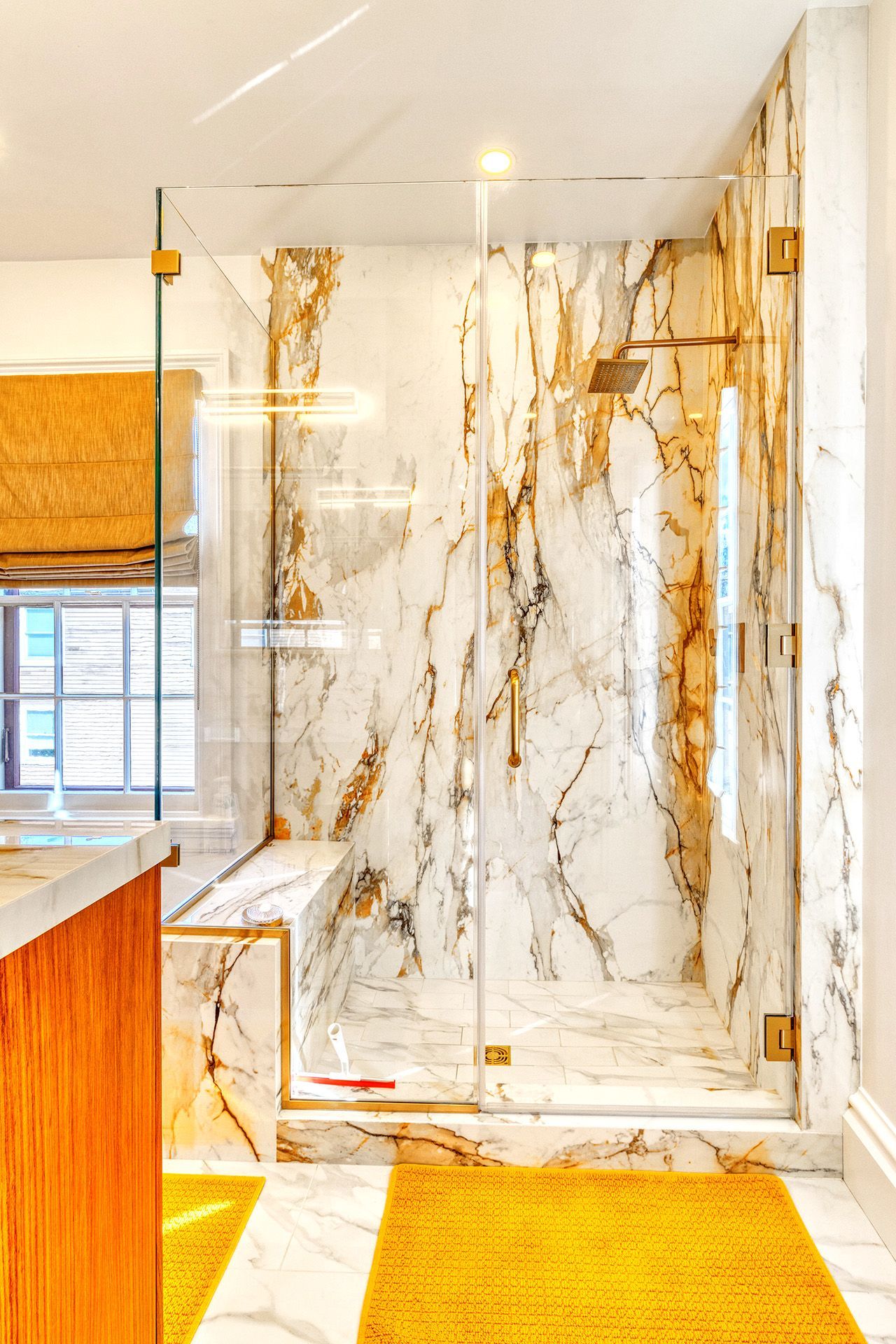 A bathroom with marble walls and a walk in shower.