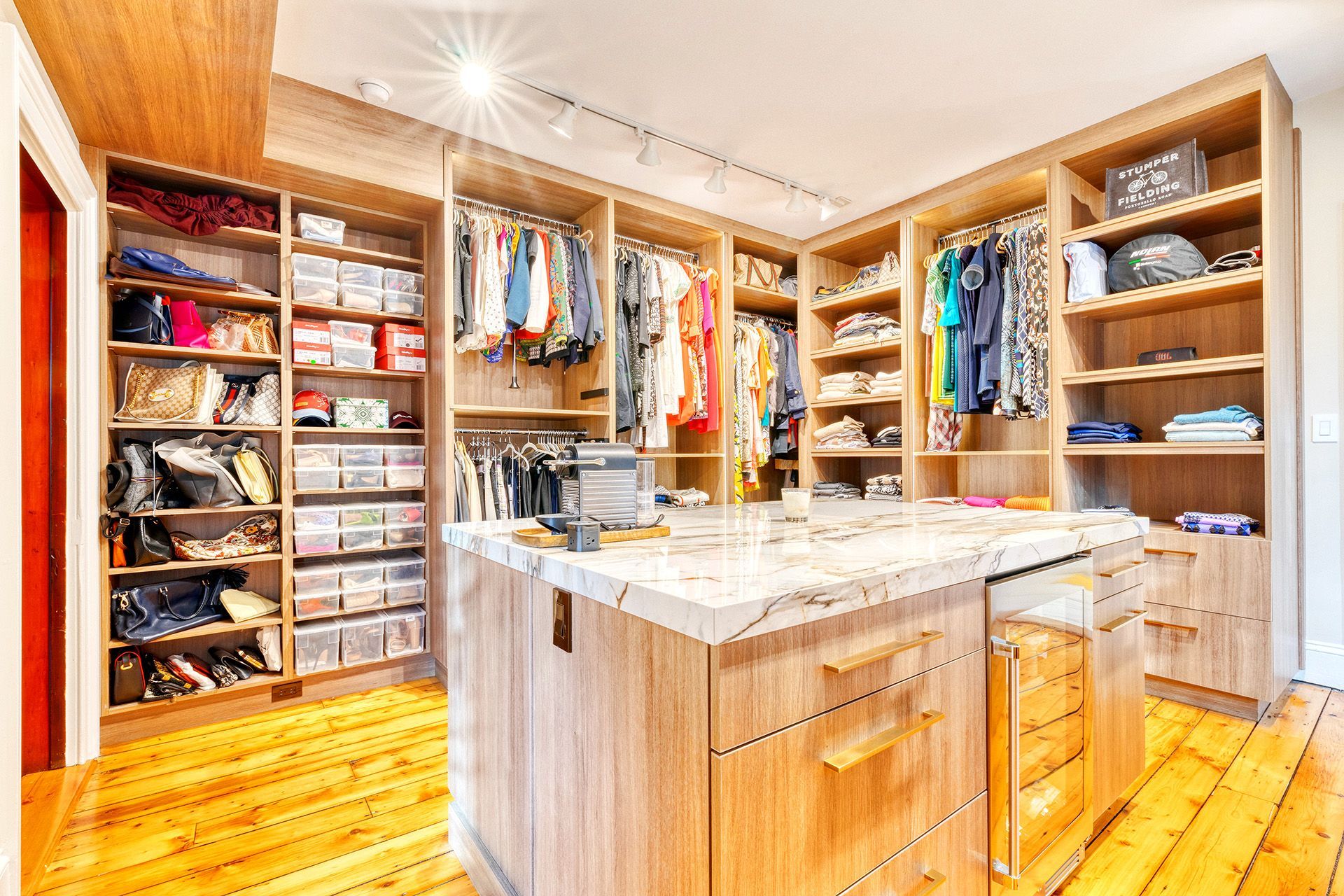 A walk in closet filled with lots of clothes and a large island.