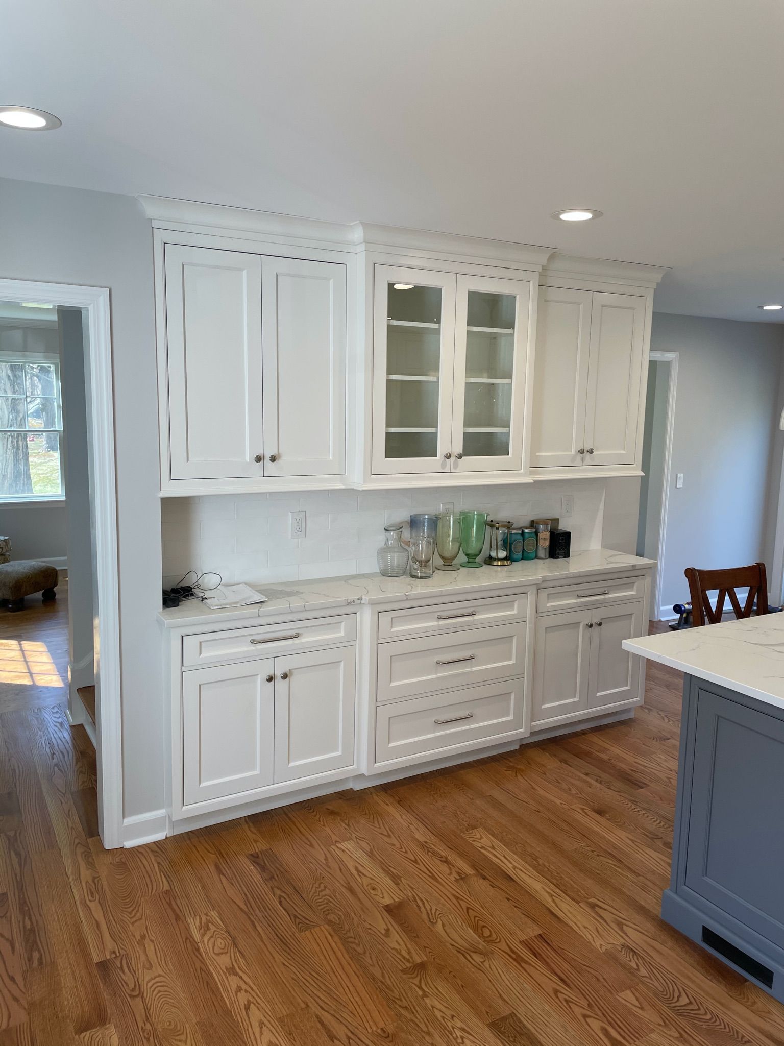 A kitchen with white cabinets and hardwood floors.
