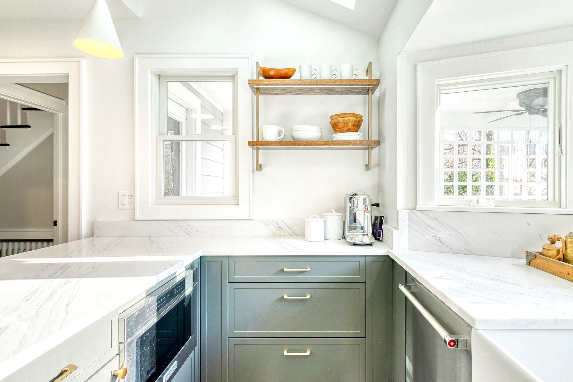 A kitchen with white cabinets , white counter tops , and a window.