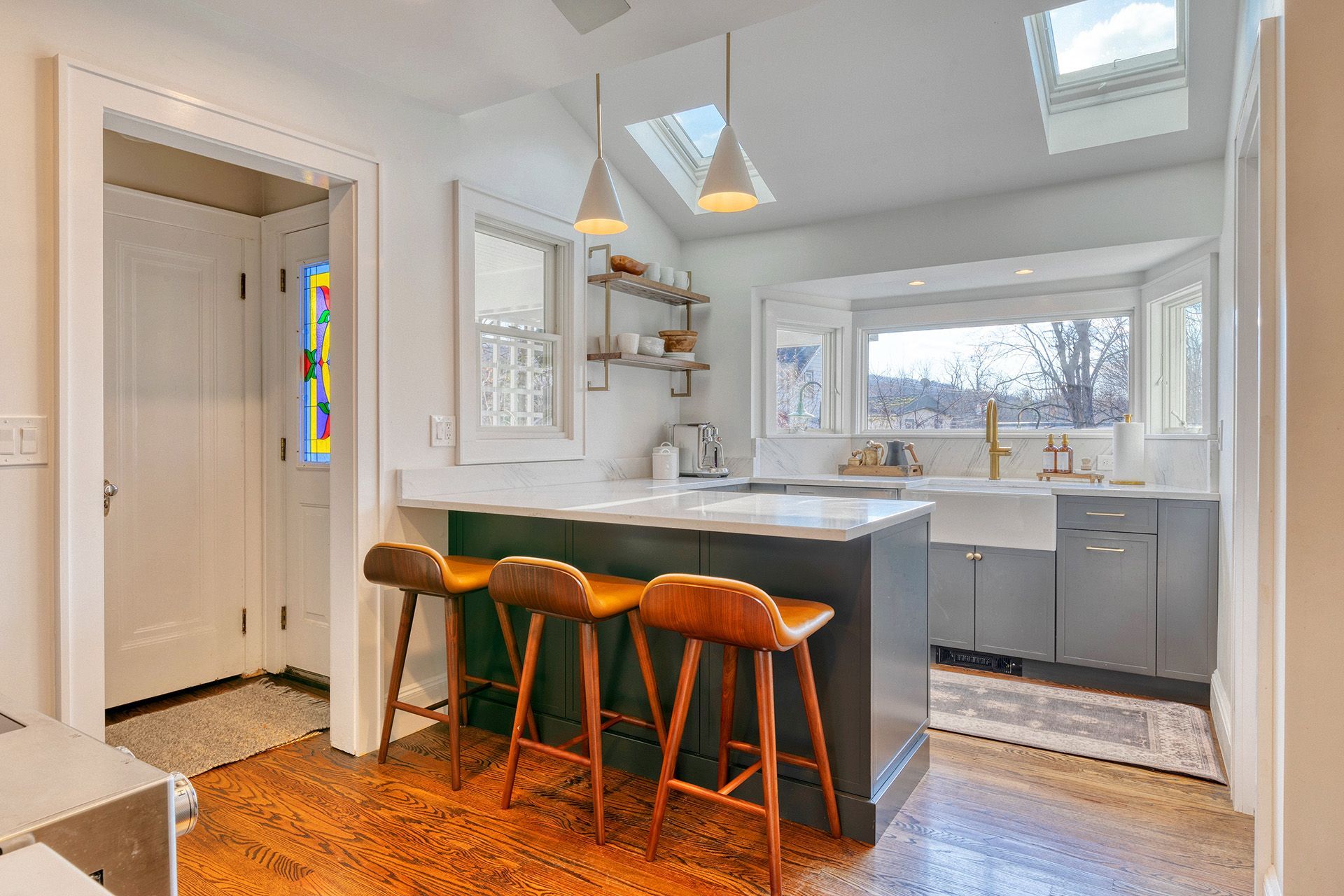 A kitchen with a large island , stools , a sink and a skylight.