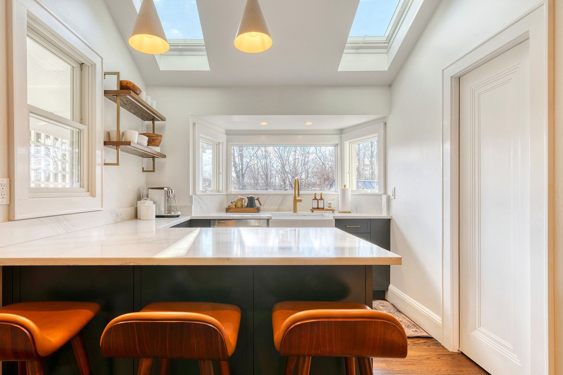 A kitchen with a large island , stools and a skylight.