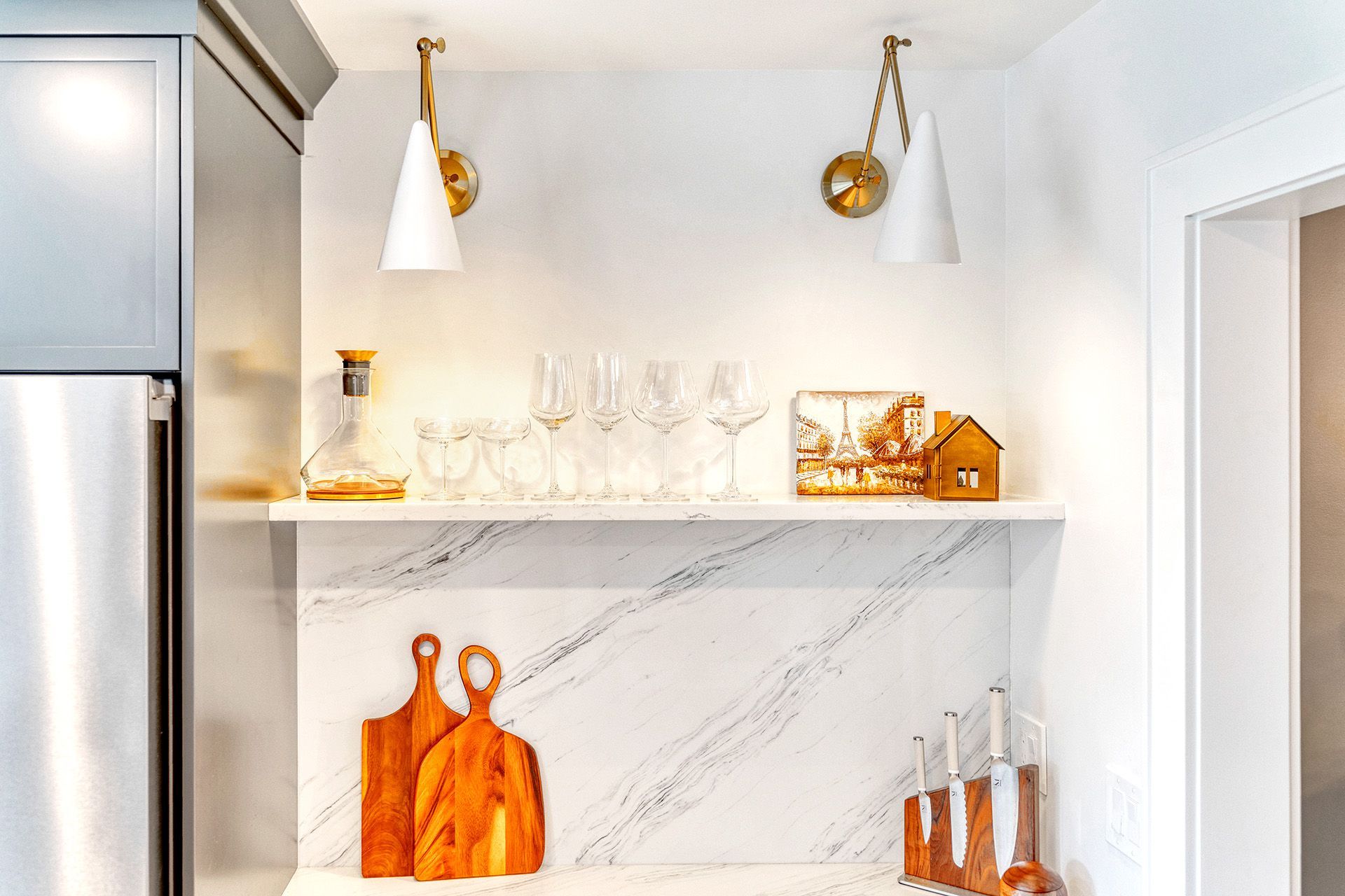 A kitchen with a shelf filled with cutting boards and glasses.