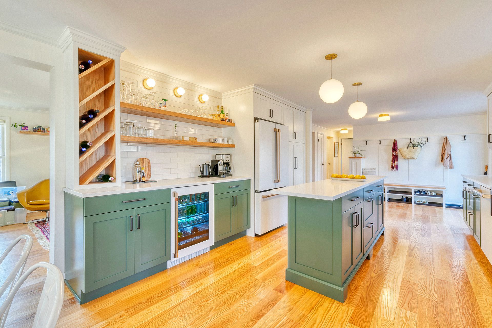 A kitchen with green cabinets , white cabinets , hardwood floors and a wine cooler.
