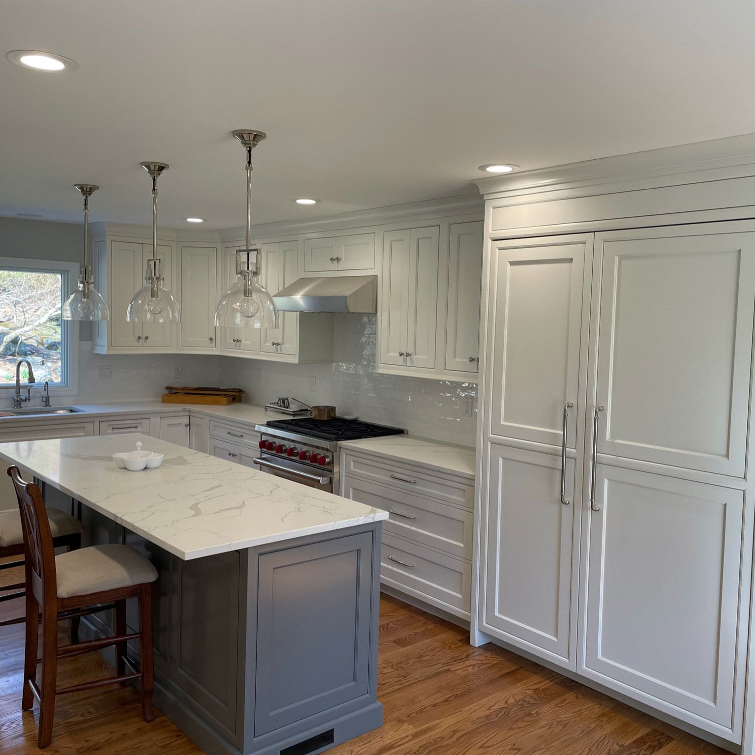 A kitchen with white cabinets and a large island in the middle