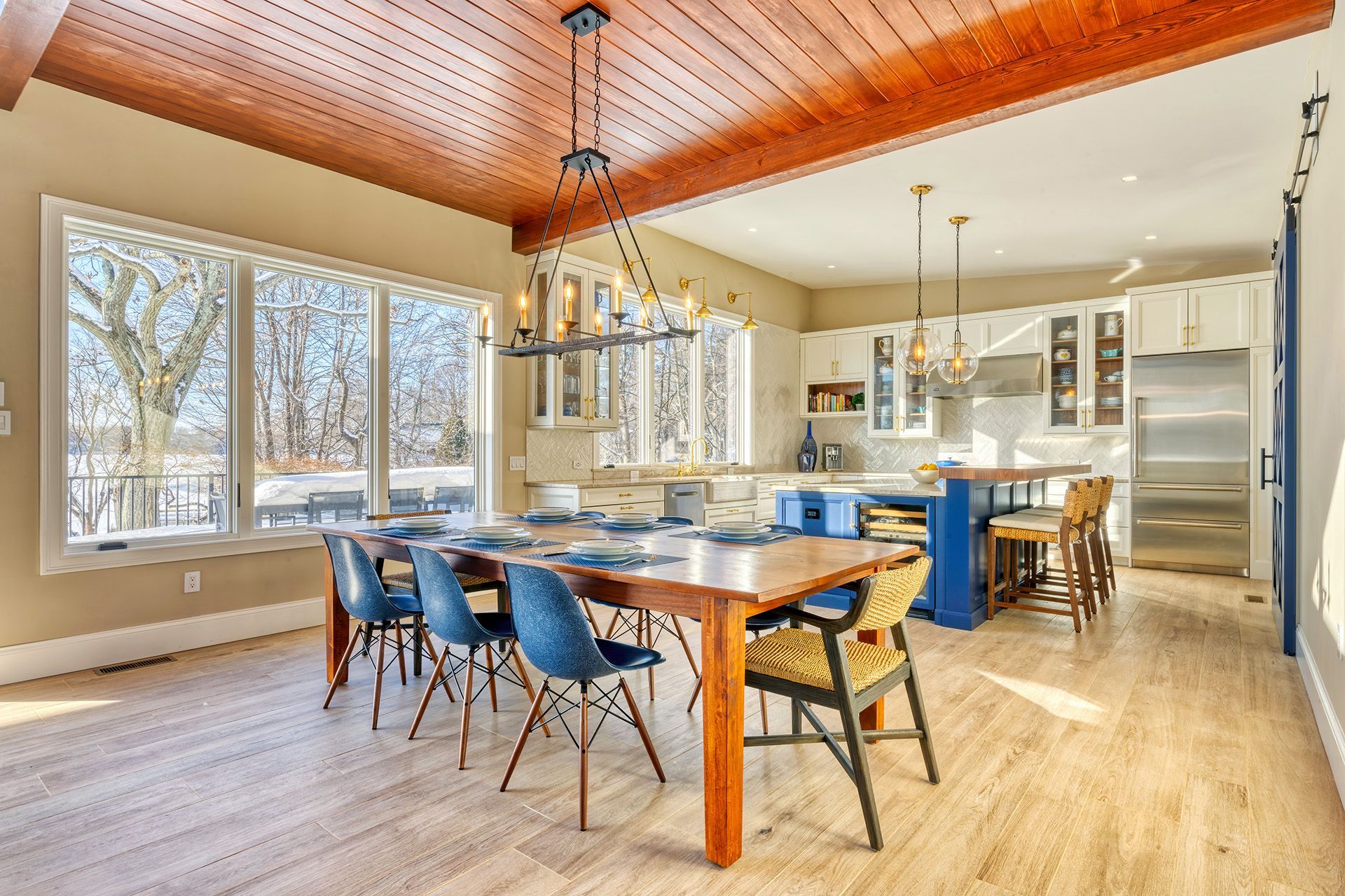 Spacious open-concept dining room and kitchen with a large table, blue chairs, and a central kitchen island.