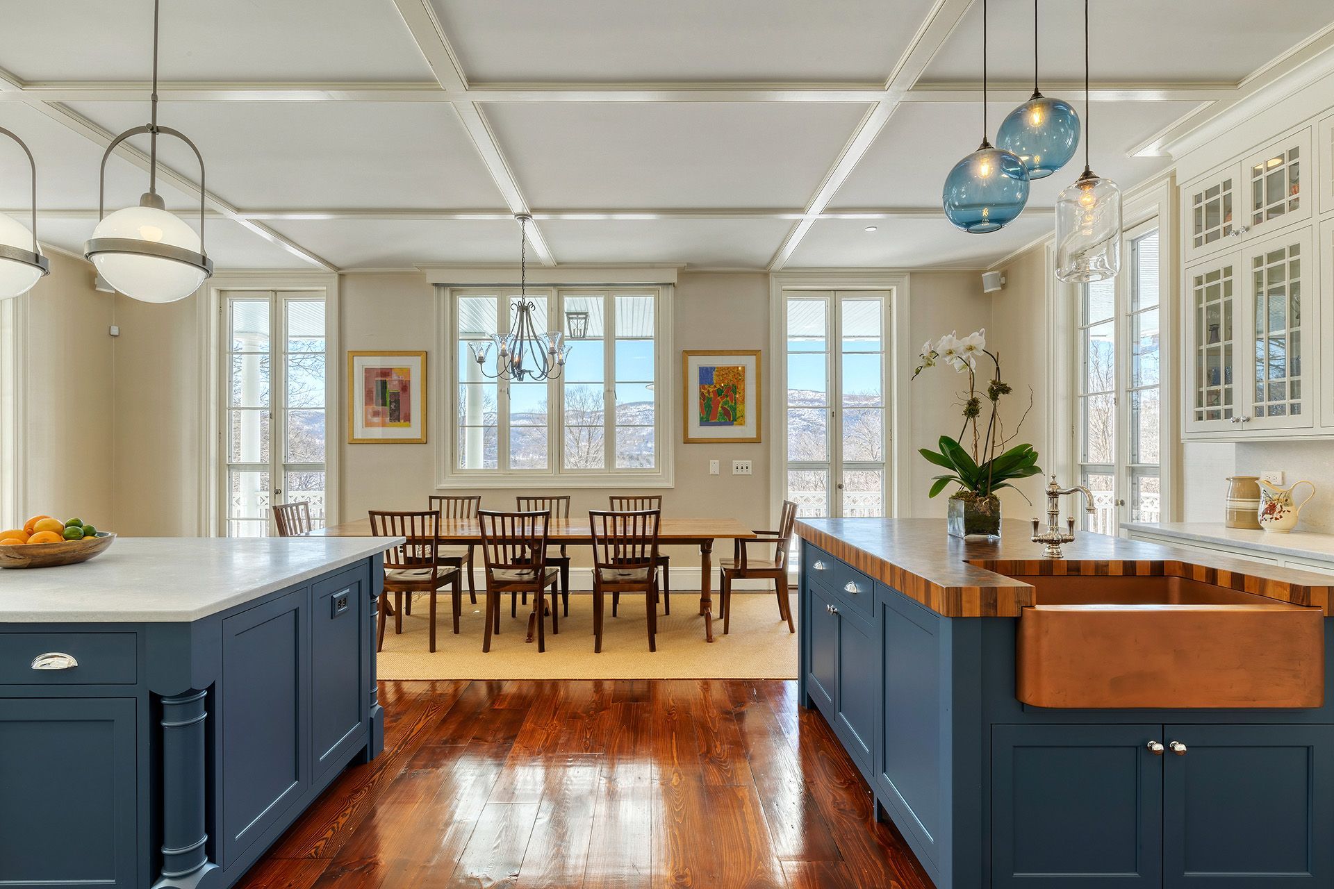 White kitchen with a large island, stainless steel appliances, and a bowl of fruit.