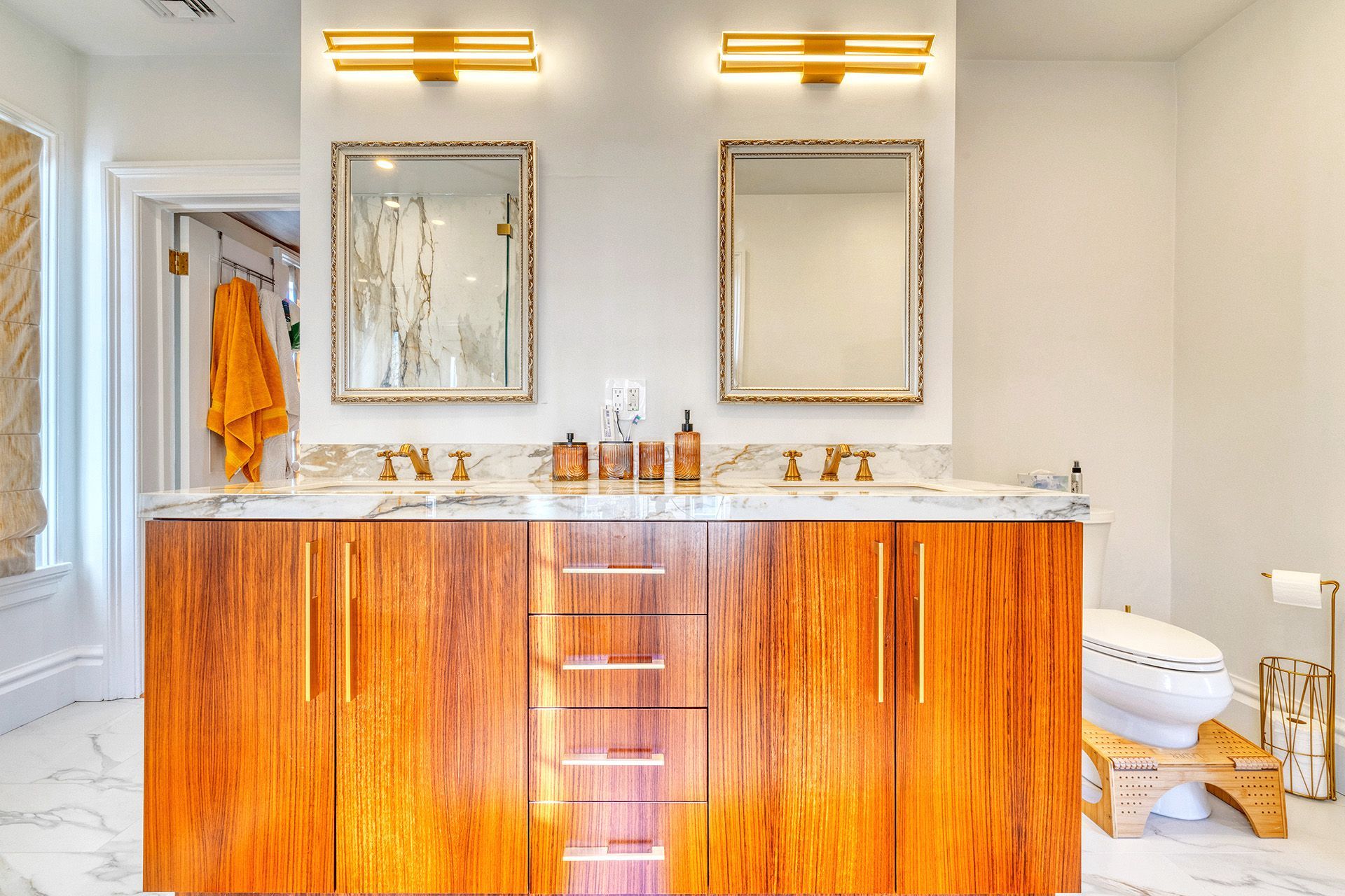 A bathroom with two sinks , two mirrors and a toilet.