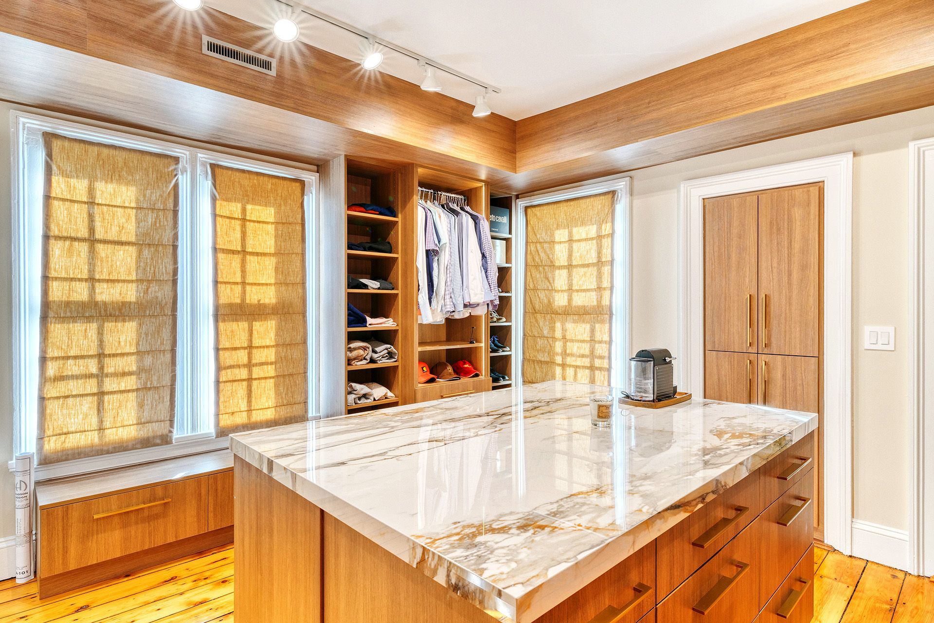 A walk in closet with a large island in the middle of the room.