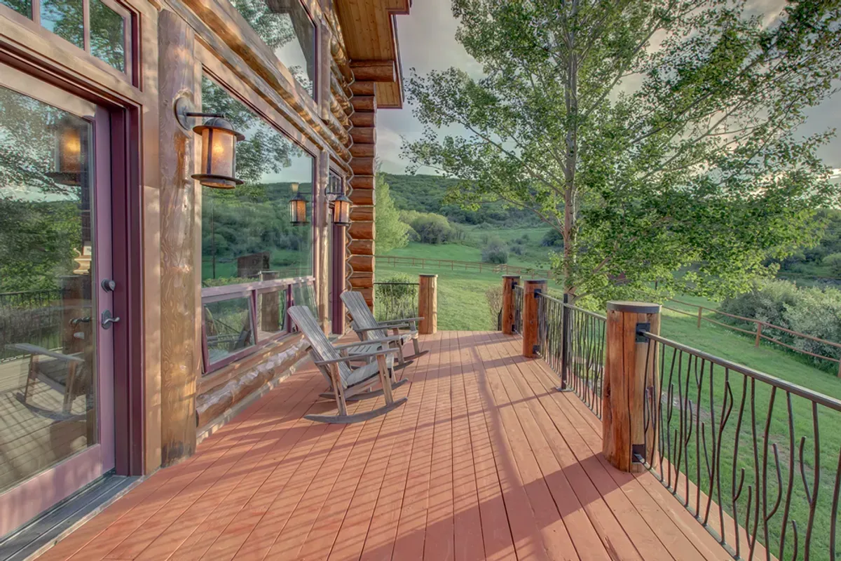 There is a large deck with rocking chairs on it.