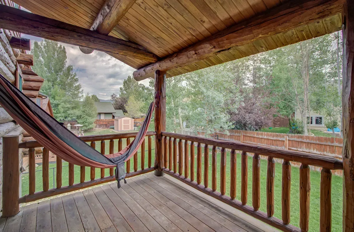 A hammock is hanging over a wooden deck.