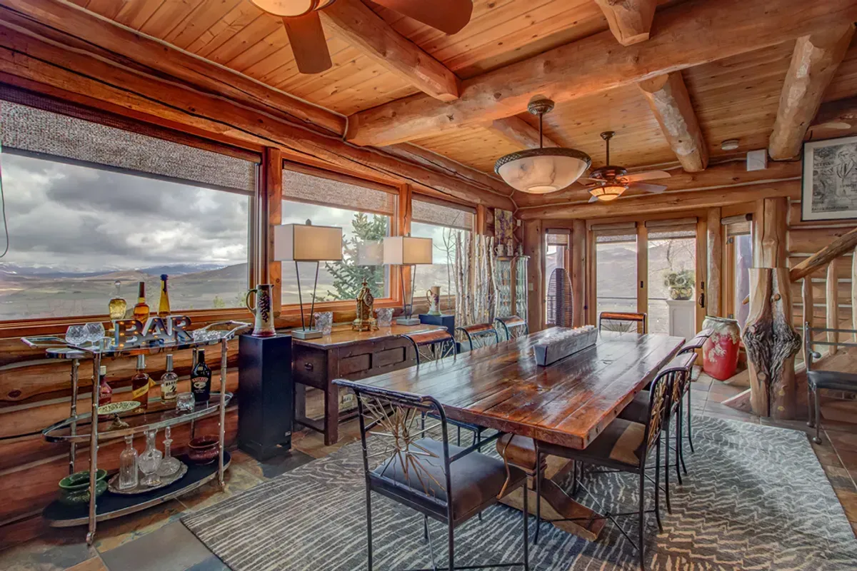 A dining room in a log cabin with a long wooden table and chairs.