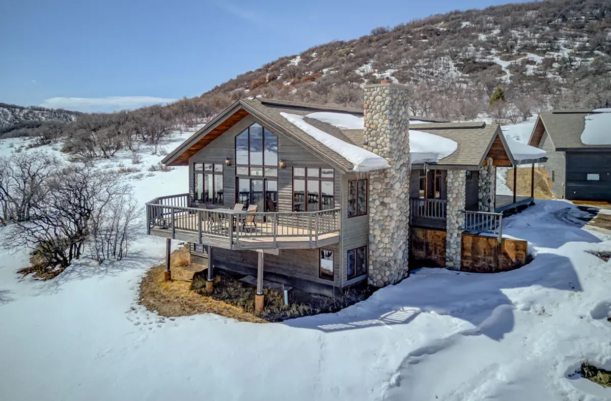 A large house is sitting on top of a snow covered hill.