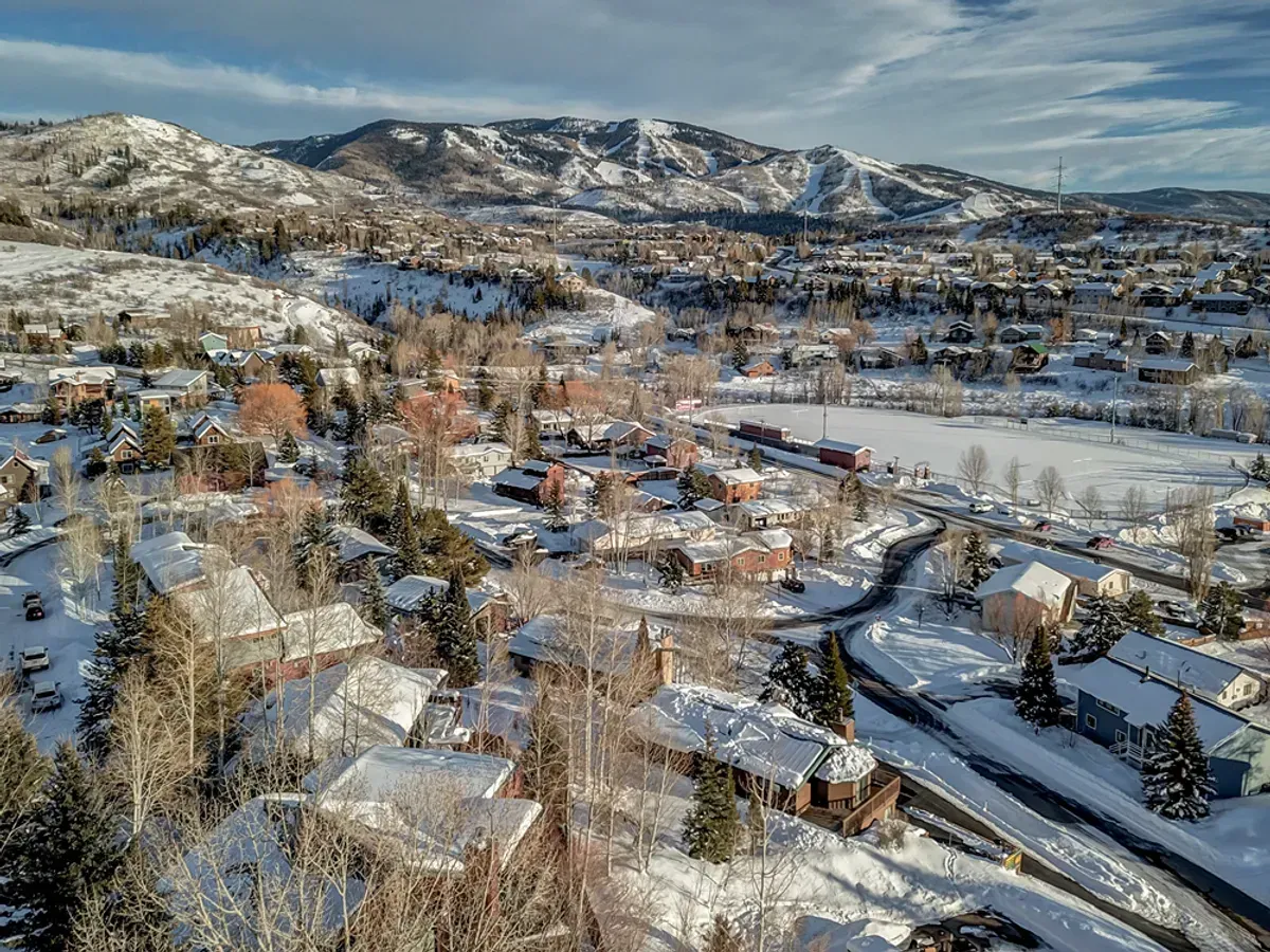 An aerial view of a snowy town with mountains in the background.