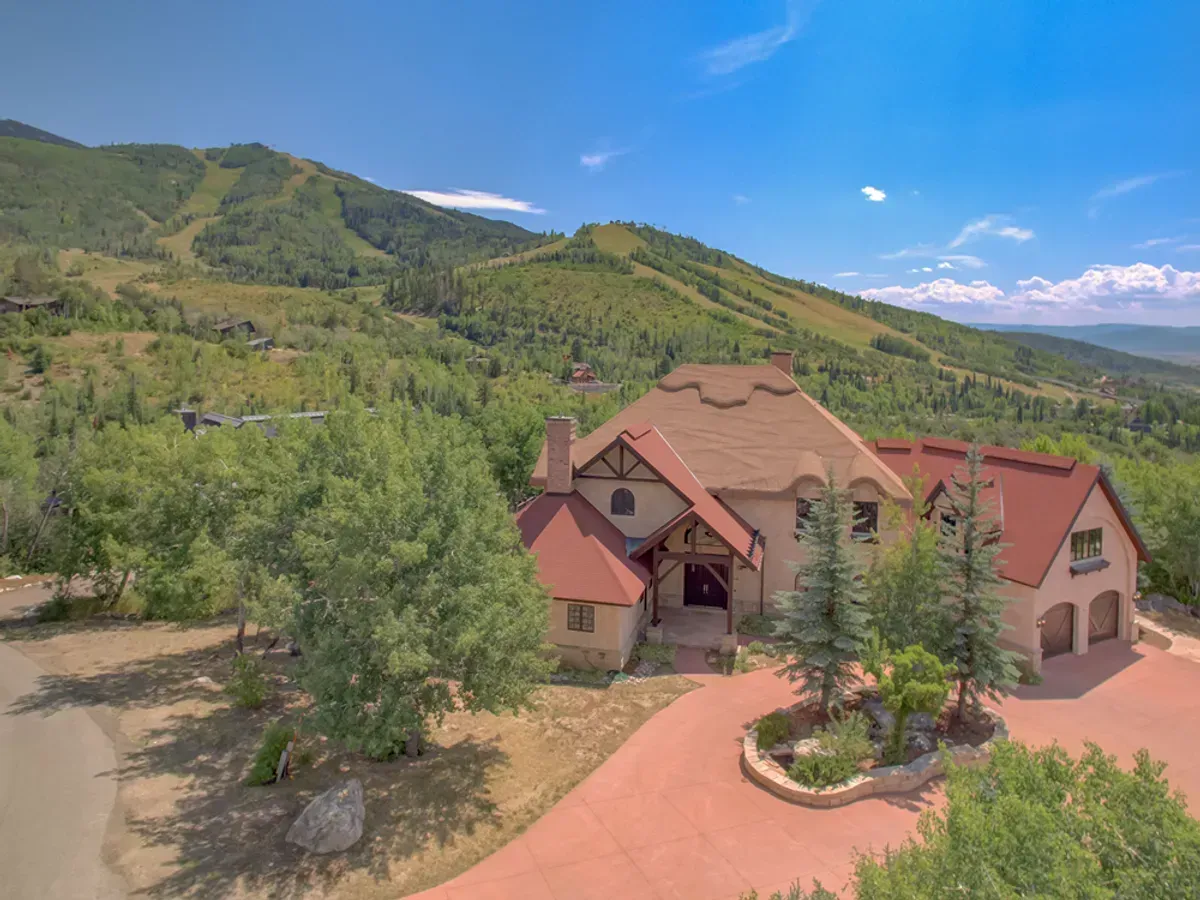 An aerial view of a large house surrounded by trees and mountains.