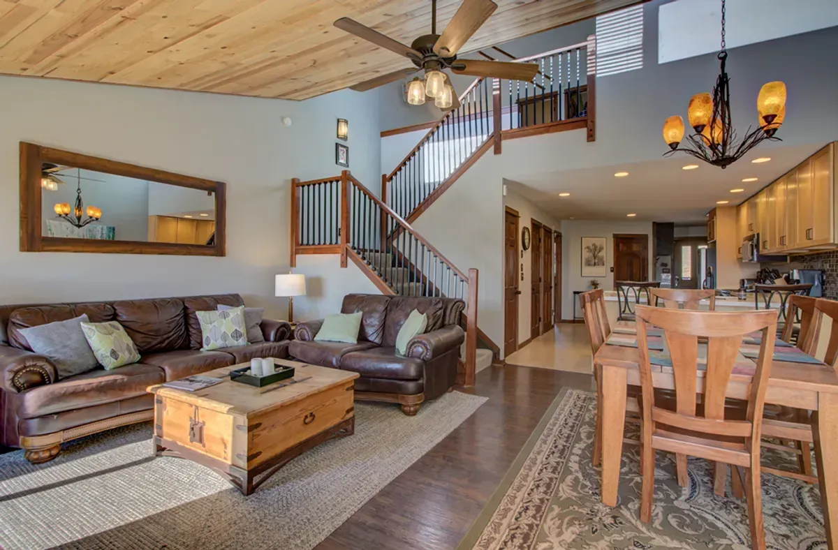 A living room with a couch , table , chairs and a ceiling fan.
