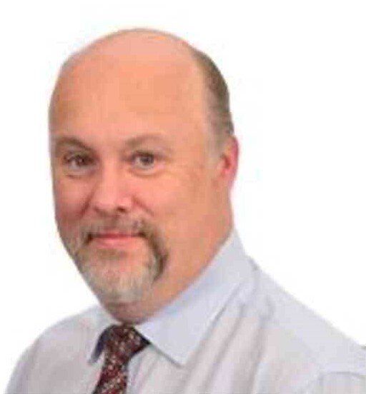 A bald man with a beard is wearing a white shirt and tie.