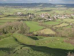 A view of a lush green valley with a village in the distance.