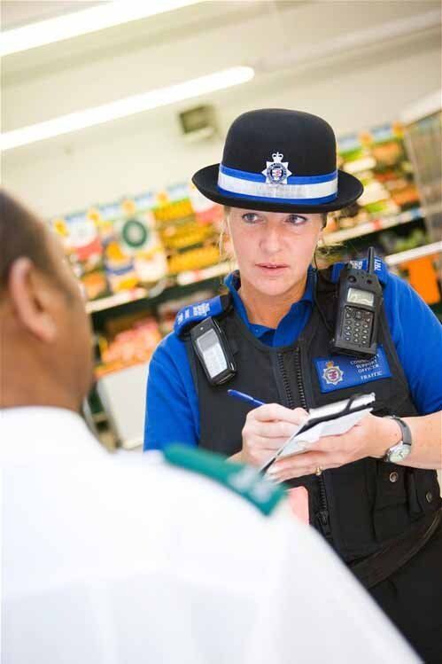 A woman in a police uniform is talking to a man in a store.