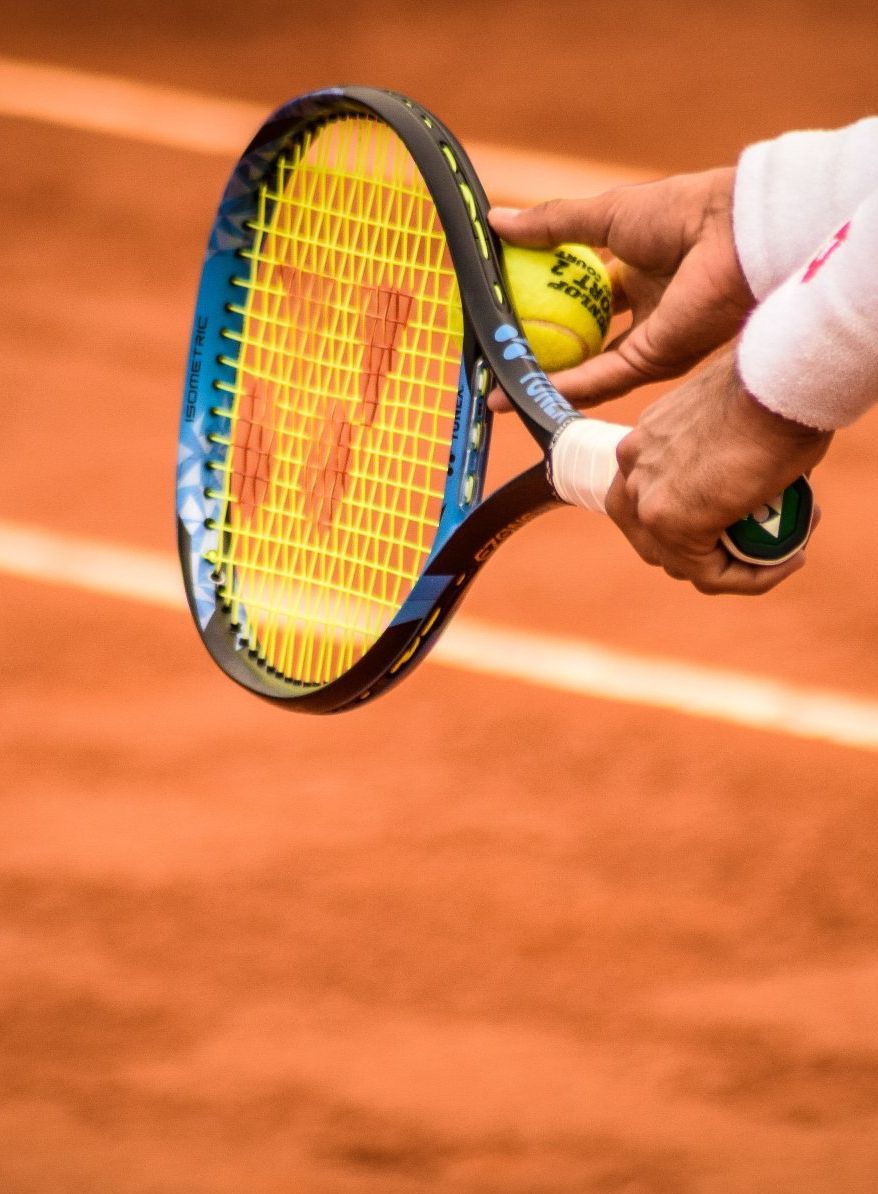 A person is holding a tennis racket and a tennis ball on a tennis court.