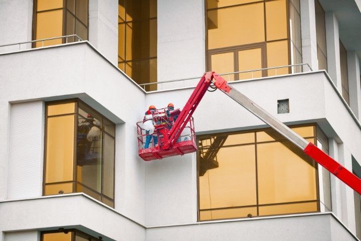 Painters in a boom lift working on a commercial building.