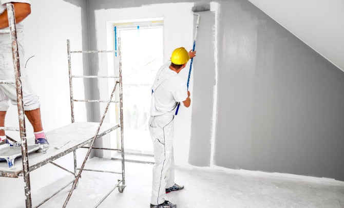 Professional painter on scaffolding painting an interior wall.