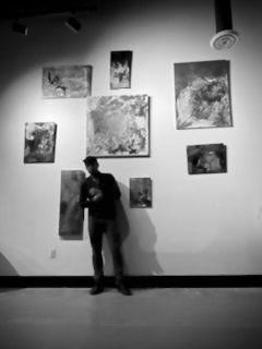 A man is standing in front of a wall with paintings on it