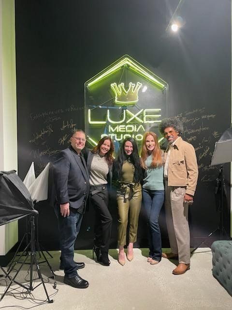 A group of people are posing for a picture in front of a neon sign.