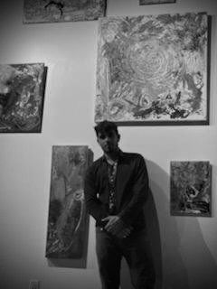 A man is standing in front of a wall with paintings on it.