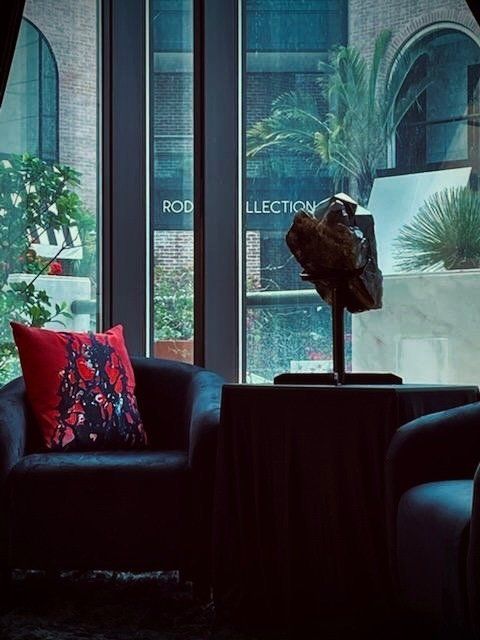 A chair with a red pillow sits in front of a window.