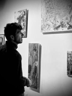 A man is looking at a painting on a wall in a black and white photo.