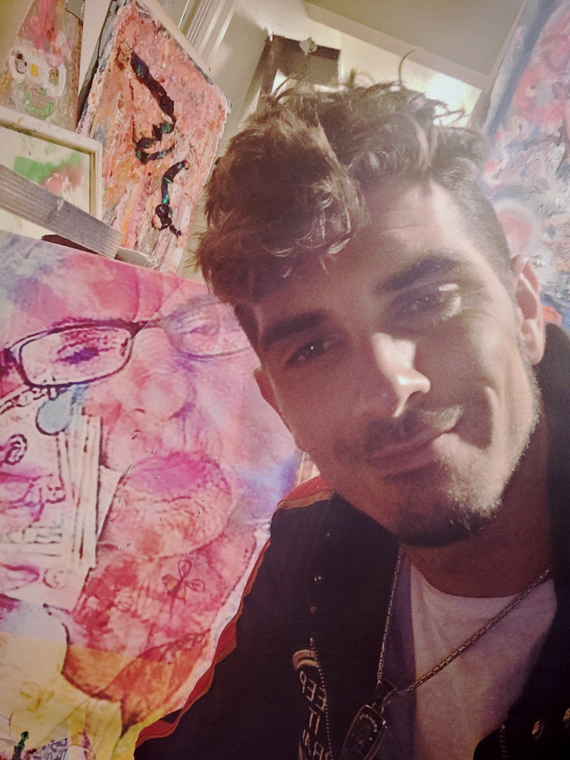 A man is taking a selfie in front of a painting.