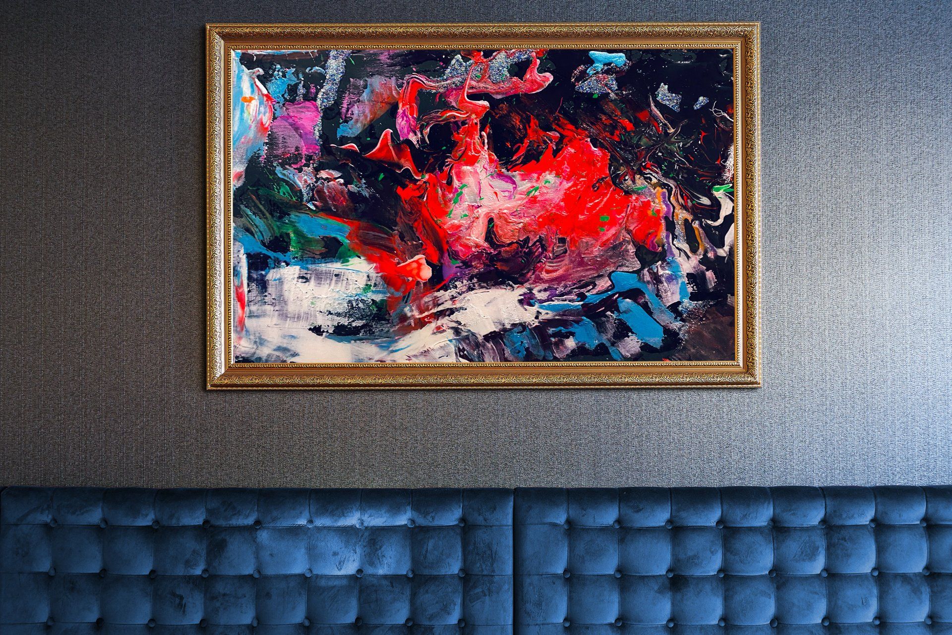 A painting is hanging on a wall next to a blue couch.