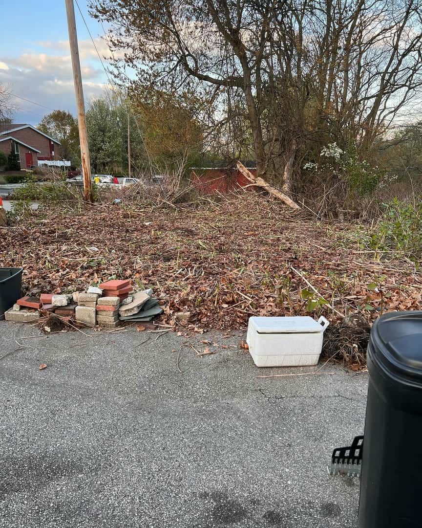 A white cooler is sitting on the side of the road next to a trash can.