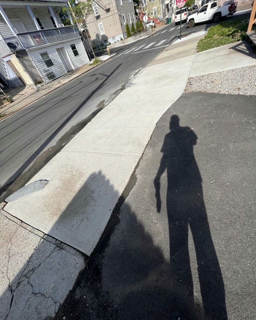 A shadow of a person standing on a sidewalk