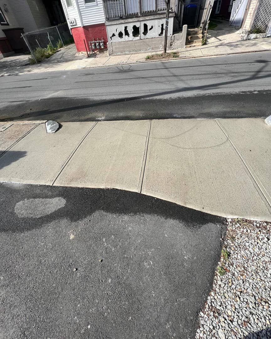 A sidewalk with a lot of water on it is next to a road.