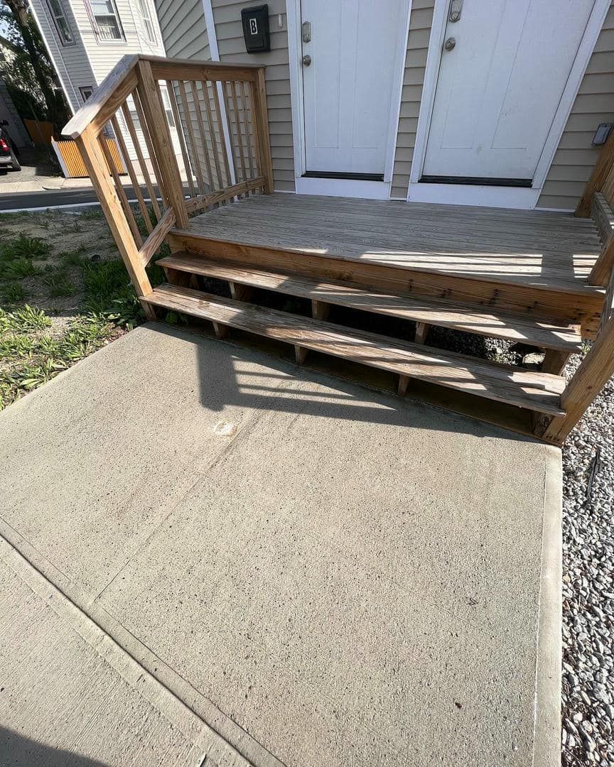 A wooden porch with stairs leading up to a house.