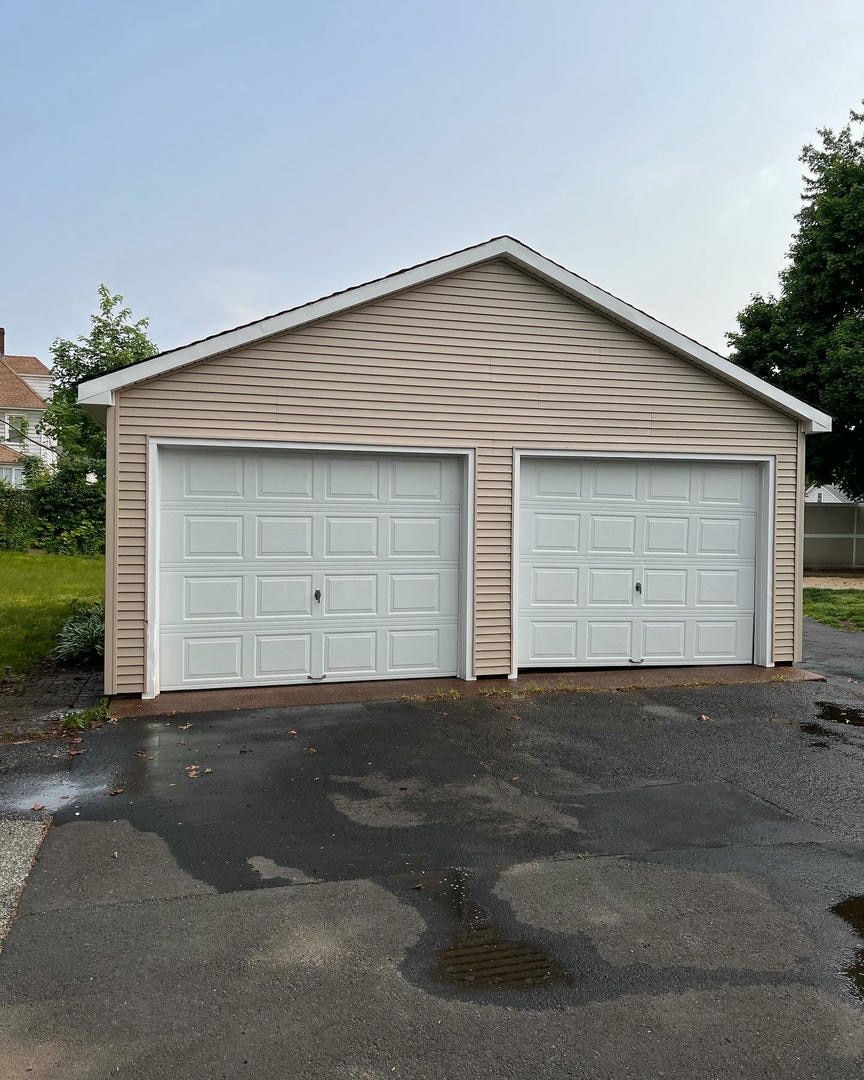 A garage with two white garage doors on a rainy day