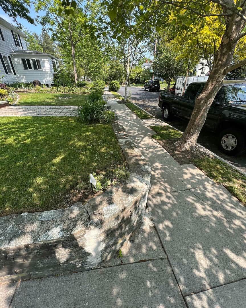 A black truck is parked on the side of the road next to a sidewalk.