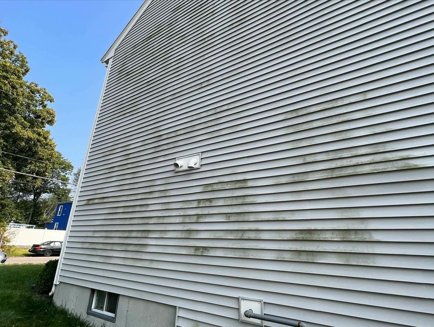 A white house with a lot of stains on the side of it.