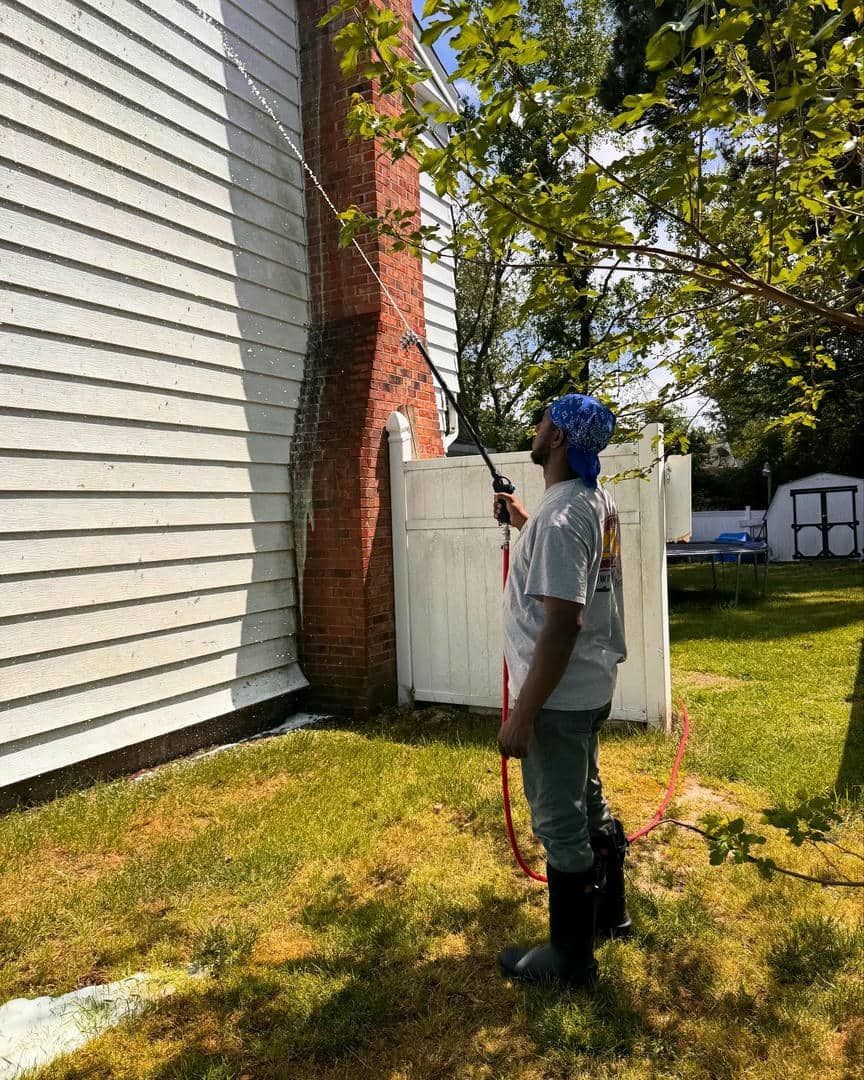 A man is spraying a house with a hose.