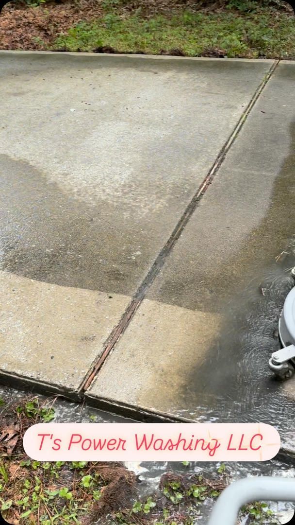 A person is cleaning a concrete driveway with a pressure washer.
